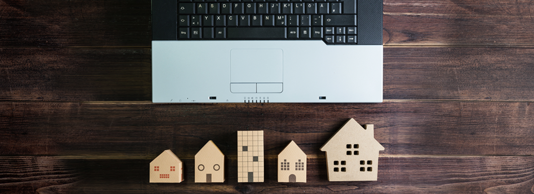 Modellini di case in legno vicino a un computer portatile