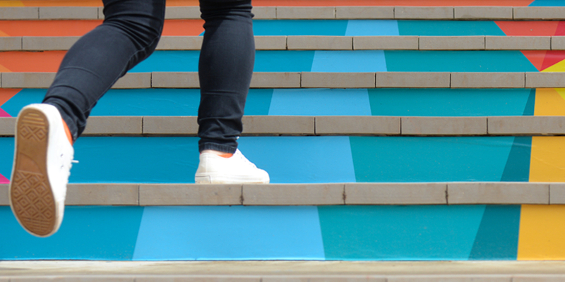 Una persona sale una scalinata colorata